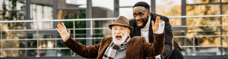 Compass Associates - Elderly Care Domiciliary and Homecare - An elderly man being pushed in a wheelchair by a younger man with both of them looking very happy and enjoying themselves