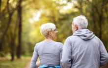 Compass Associates - elderly couple looking at each other and holding hands with their backs to the camera, walking in a park/green area