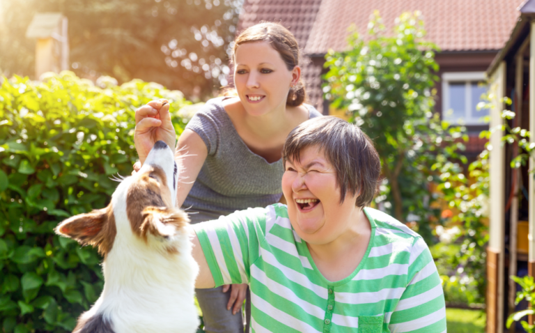 Compass Associates - Two ladies outside in a garden playing with a dog and feeding it treats