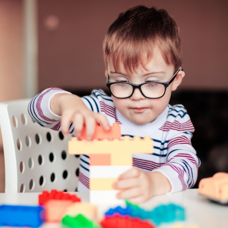 Compass Associates - Specialist Care - Candid photo of a small child sat at a table playing with Duplo bricks